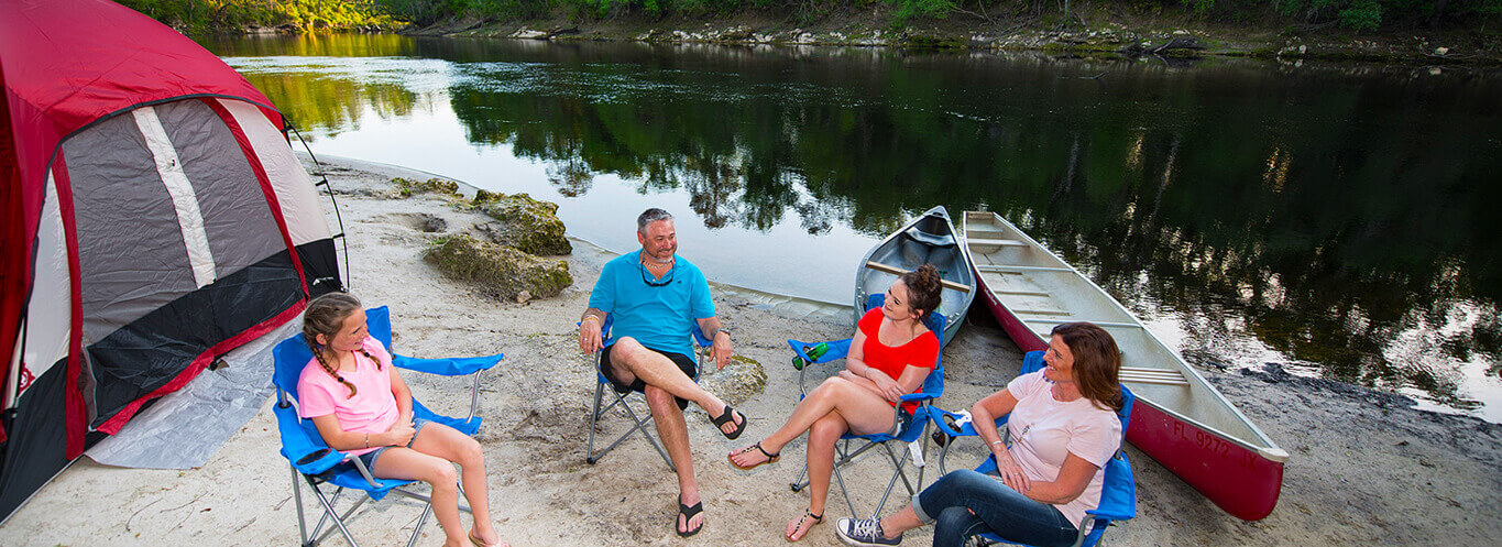 campers sitting in chairs by lake in suwannee campground
