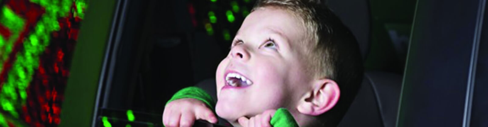 Child looks out a car window at Christmas lights